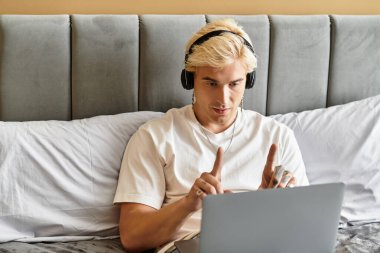 Kulaklıklı genç bir adam yatağında oturuyor, sanal bir toplantıda..