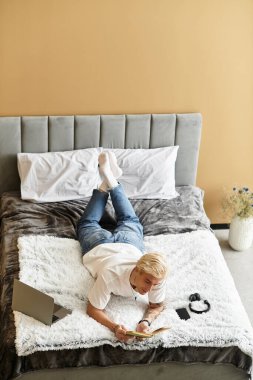 Genç adam rahat bir yatakta uzanıyor, huzurlu bir öğleden sonra bir deftere yansıtıyor ve yazıyor..