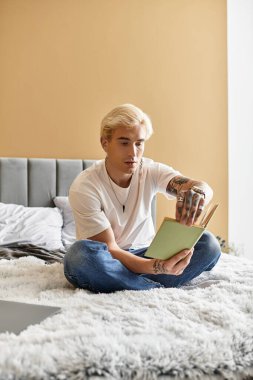 Genç, şık bir adam yumuşak bir yatakta bacak bacak üstüne atarak oturur, dikkatle okur ve anın tadını çıkarır..