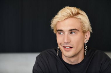 Modern bir apartman dairesinde dinlenirken sarışın yakışıklı genç adam sıcak bir şekilde gülümsüyor..