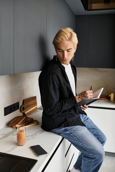Молодой человек сидит в шикарной квартире, сосредоточенный на записи в блокноте, источая вдохновение.