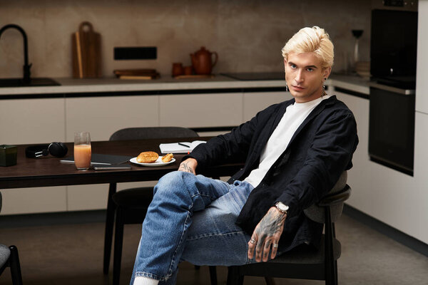 Молодой человек удобно сидит за стильным столом, наслаждаясь завтраком в шикарной квартире.