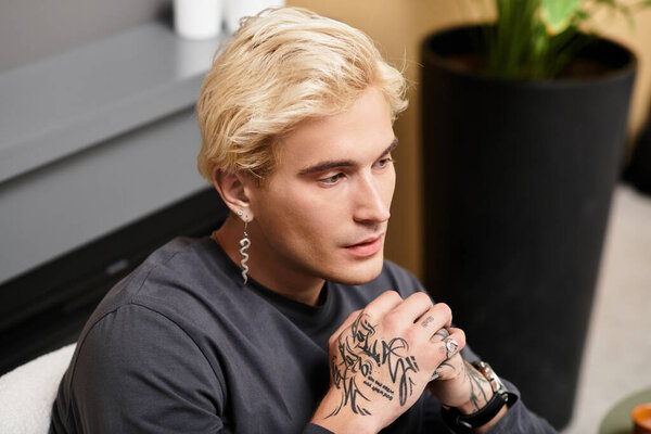 Молодой, красивый мужчина спокойно размышляет в современной квартире, украшенной растениями.