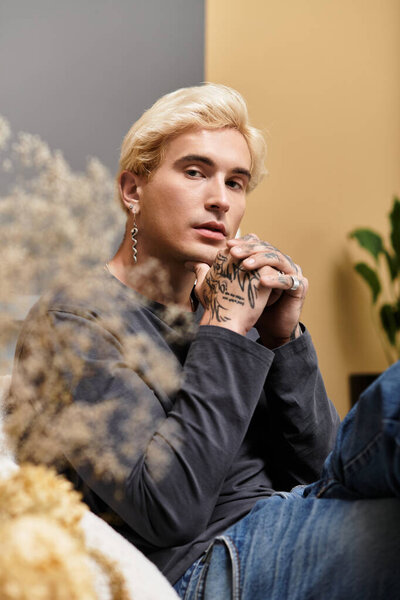 Очаровательный молодой человек расслабляется в современной квартире, демонстрируя свой стиль и татуировки.