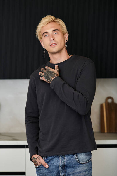 Молодой и привлекательный мужчина уверенно стоит в стильной квартире, излучающей шарм.