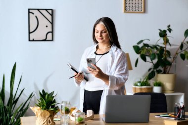 Waardenburg sendromu olan bir kadın ofisinde duruyor, notları gözden geçiriyor ve telefonunu kullanıyor..