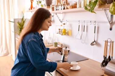 Beyaz perçemli bir kadın evinde kahve hazırlamak için mola verir.