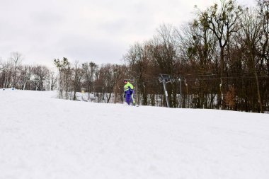 Sakallı bir adam kar yamacında kayak yapıyor, kışın soğuğunu kucaklıyor..