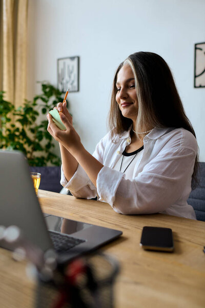 Женщина с синдромом Варденбурга работает из дома, фокусируясь на своих задачах с улыбкой.