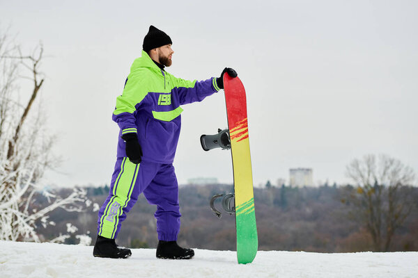 Бородатый мужчина в разноцветной верхней одежде готовится кататься на сноуборде по снежному склону, наслаждаясь зимними развлечениями.