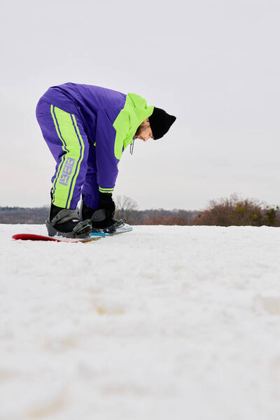 Бородач подготавливает сноуборд на снежном склоне зимой в спокойной атмосфере.