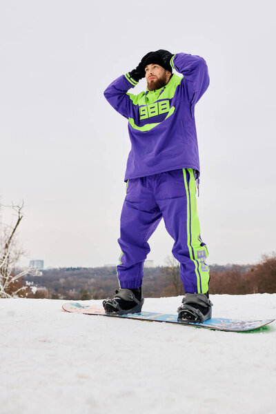 Бородач готовится к сноуборду на снежном склоне, демонстрируя свою стильную зимнюю экипировку.