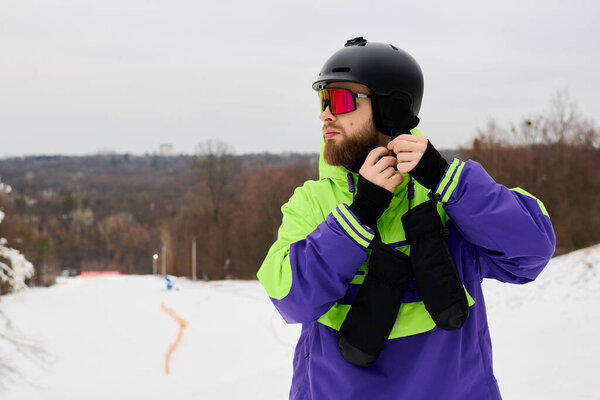 Бородатый мужчина готовится к сноуборду на красивом снежном склоне, демонстрируя свою спортивную экипировку.