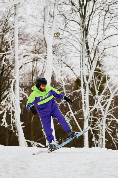 Бородач наслаждается сноубордом на снежном склоне в окружении деревьев зимой.
