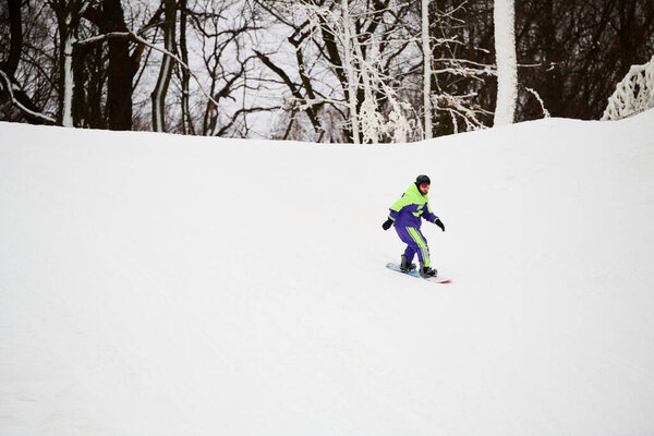 A man skillfully snowboards down a snowy slope, embracing winter's beauty overhead.