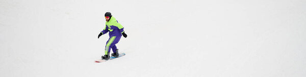 Бородач умело катается на сноуборде по нетронутому снежному склону, наслаждаясь зимними видами спорта, знаменем