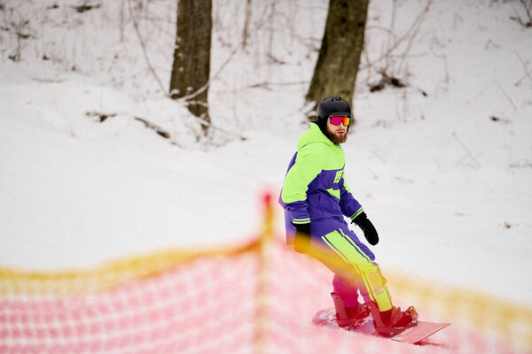 Бородатый человек умело перемещается по снежному склону во время сноуборда, демонстрируя свои навыки..