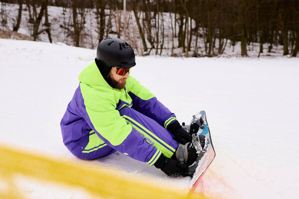 Бородач готовится к сноуборду на хрустящем снежном склоне, окруженном деревьями..