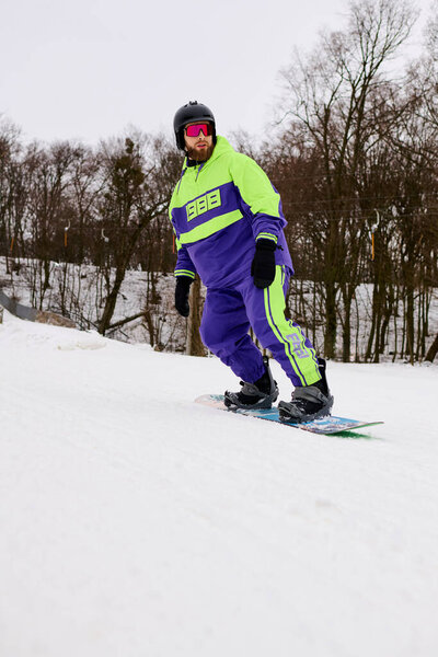 Бородач наслаждается сноубордом на снежном склоне, окруженном деревьями зимой..