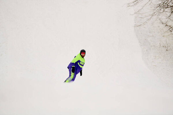 Бородач умело катается на сноуборде по снежному склону в яркий зимний день.