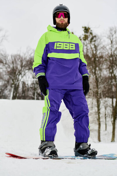 Мужчина с бородой любит кататься на сноуборде по снежному склону в яркой зимней одежде.