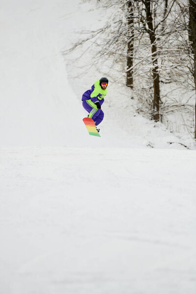 Бородач катается на сноуборде по снежному склону, демонстрируя свои навыки в зимних видах спорта..