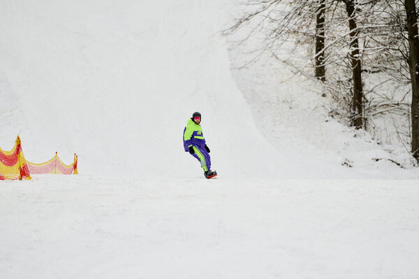 A bearded man snowboards down a pristine slope, showcasing his skills in winter gear.