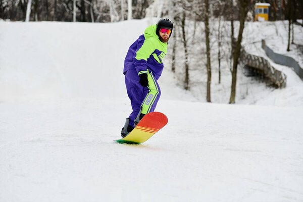 A bearded man expertly snowboards down a snowy slope in vibrant winter gear.