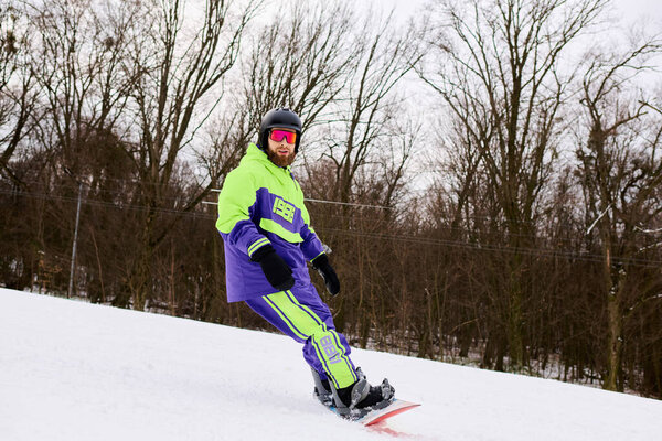 A bearded man skillfully snowboards on a snowy slope surrounded by trees, enjoying winter sports.