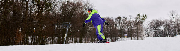 A man with a beard descends a snowy slope, showcasing snowboarding skills in winter attire, banner