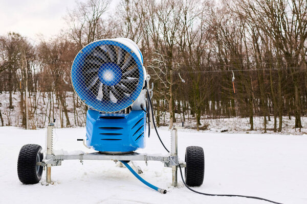 A snow machine stands ready at a snowy slope, ensuring great winter sports.