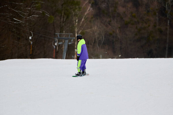 Мужчина любит кататься на сноуборде по снежному склону, в окружении зимней красоты.