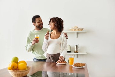 Mutlu bir Afrikalı Amerikalı çift, hamileliklerini kutlamak için birlikte kahvaltı yapıyor..