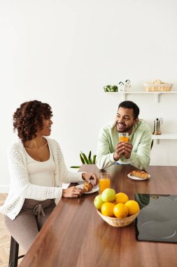 Mutlu bir çift, evde hamileliklerini kutlarken sıcak bir kahvaltı yapar..