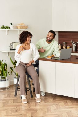 Mutlu bir çift, yeni bir bebeğe hazırlanırken mutfakta hafif bir anı paylaşır..