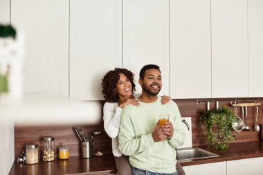 Neşeli bir çift şık mutfaklarında bir anı paylaşır, sevgi ve mutluluğu kucaklarlar..