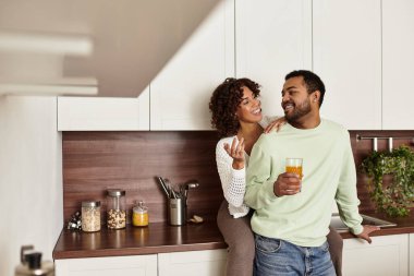 Neşeli bir Afrikalı Amerikalı çift rahatlarken şık dairelerinde kahkahalarını paylaşıyor.