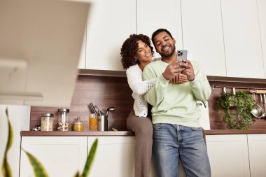 Neşeli bir Afrikalı Amerikalı çift modern mutfaklarını keşfederken kahkahalarını paylaşıyor..