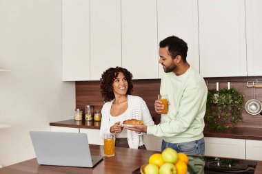 Neşeli bir Afrikalı Amerikalı çift, modern mutfaklarında samimi bir kahvaltı anı paylaşıyor..