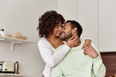 Neşeli bir Afrikalı Amerikalı çift, sevgi dolu modern evlerinde hassas bir anı paylaşıyor..