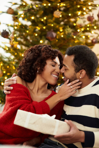 Счастливая пара разделяет нежный момент у красиво украшенной елки, обнимая любовь.