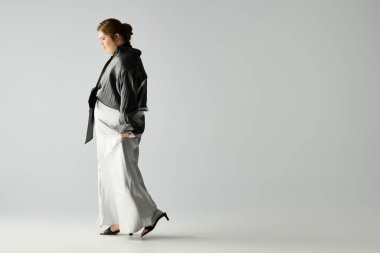 Down sendromlu genç bir kadın zarif bir kıyafetle, kendine güven ve neşe saçarak yürüyor..