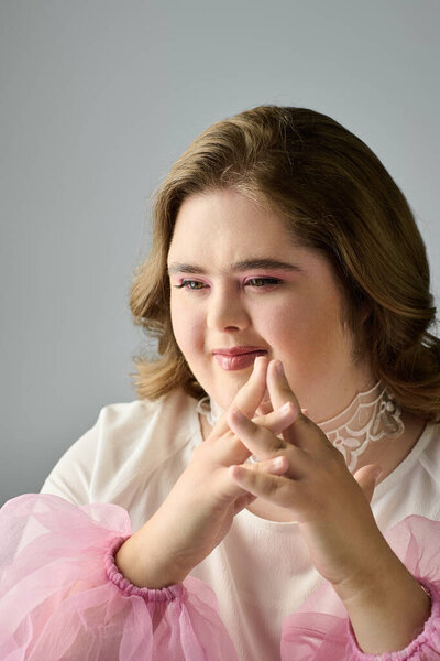A joyful young woman with Down syndrome smiles warmly, showcasing her creative side while sitting.