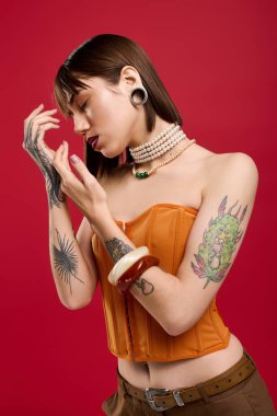 Şık giyinmiş genç bir kadın cesur bir kırmızı zemine karşı güven ve yaratıcılık gösteriyor..