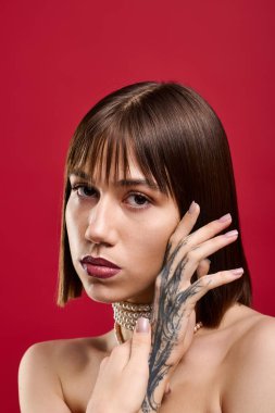 Genç, şık bir kadın zarif bir şekilde poz veriyor, eşsiz modasını ve cesur aksesuarlarını vurguluyor..