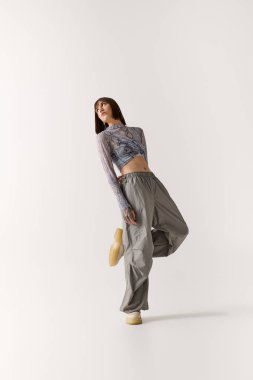 Kendine güvenen genç bir kadın, kendine has tasarımları olan şık kıyafetler sergiliyor..