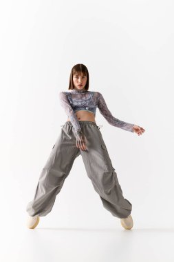 Moda kıyafetli genç bir kadın zarif bir şekilde arka planda poz veriyor, tarzını ifade ediyor..