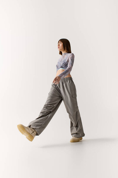 Fashionable young woman walks confidently in trendy attire with a vibrant, minimalistic backdrop.