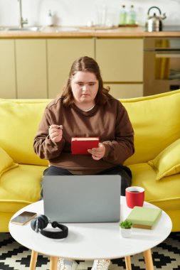 Down sendromlu genç bir kadın evinde yaratıcı aktivitelere katılıyor, cihazlarına odaklanıyor..