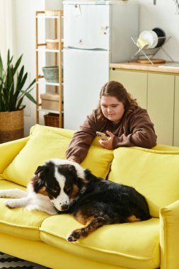 Down sendromlu genç bir kadın evinde dinlenirken köpeğiyle neşeli bir anı paylaşıyor..